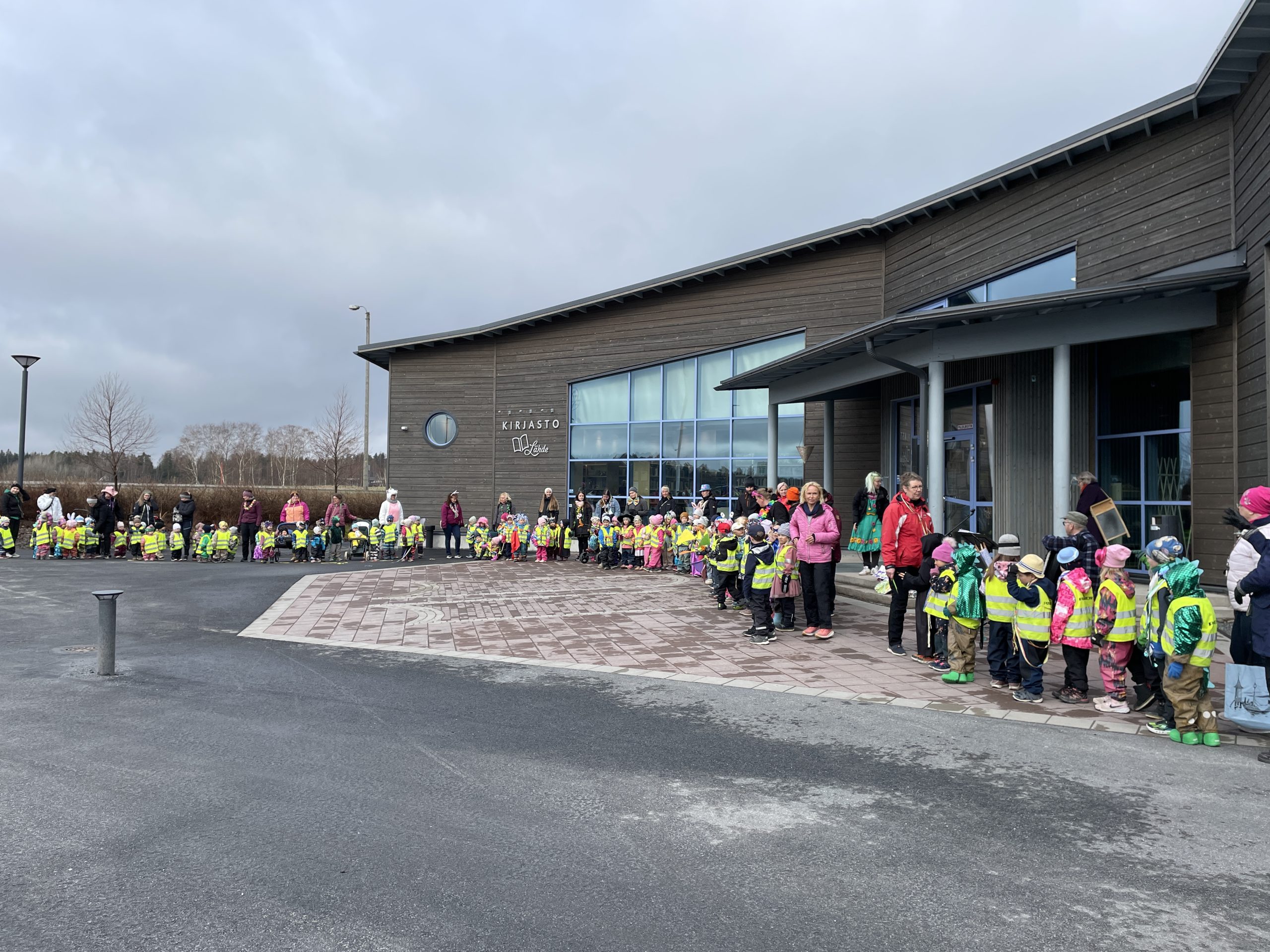 Peiponpellon päiväkodin vappukulkue kirjaston edessä.